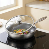 Stainless steel frying pan holding vegetables beneath a tilted glass lid with a silver knob on a black induction cooktop.