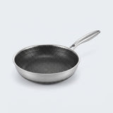 Stainless steel frying pan with a dark honeycomb interior and long silver handle on a light gray background.
