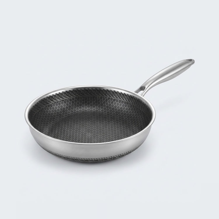 Stainless steel frying pan with a dark honeycomb interior and long silver handle on a light gray background.