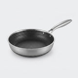 Stainless steel frying pan with a dark honeycomb interior and polished silver handle on a light gray background.
