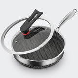 A stainless steel frying pan with a black non-stick honeycomb-coated interior, shown with a clear glass lid featuring a black handle and red accent ring, on a light gray background.
