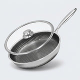 Stainless steel frying pan with a honeycomb interior and tilted glass lid with a silver knob on a light gray background.