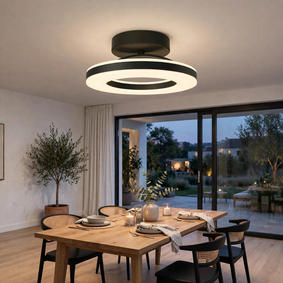 Modern circular LED ceiling light fixture with a black and white design, installed on the ceiling of a contemporary dining room with a wooden table and chairs.