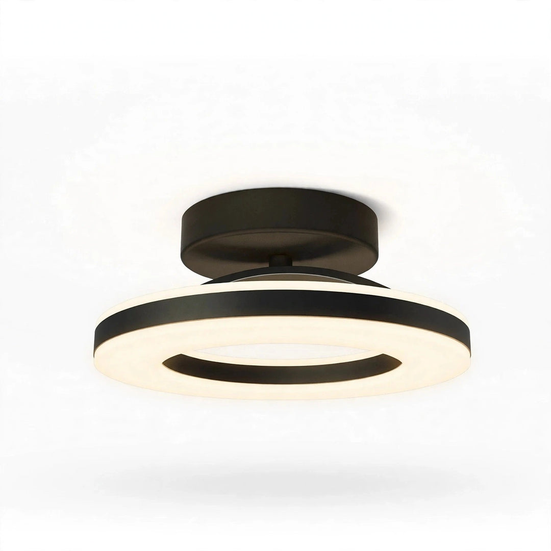 A modern semi-flush mount ceiling light fixture with a matte black metal frame and a glowing warm white LED ring, shown against a plain white background.