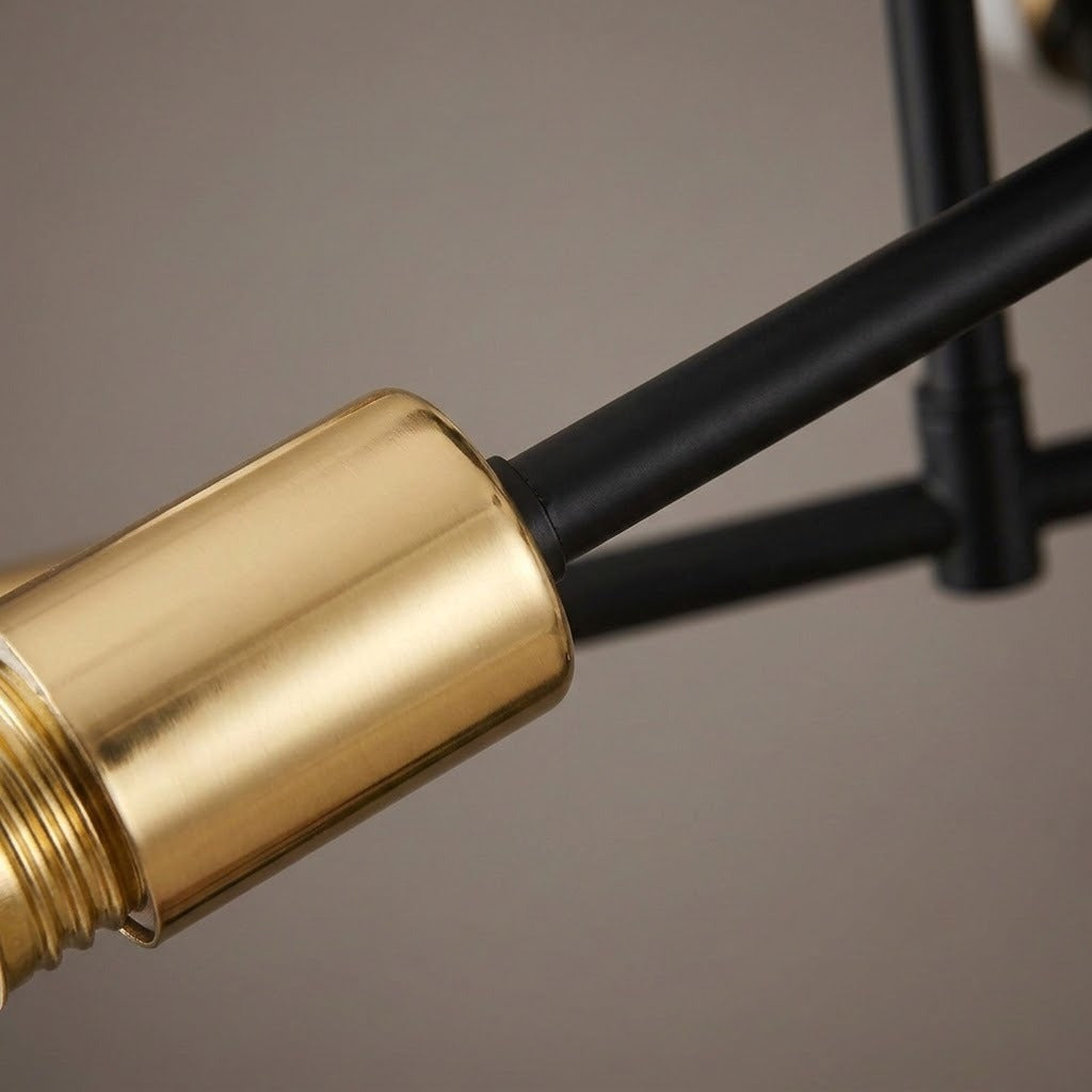 A close-up of the chandelier shows a gold-toned socket attached to a matte black arm against a gray background.