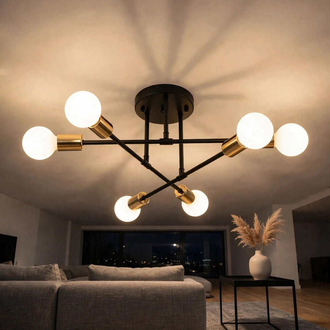 A black chandelier with gold-toned sockets and six glowing white globe bulbs hangs above a gray sofa.