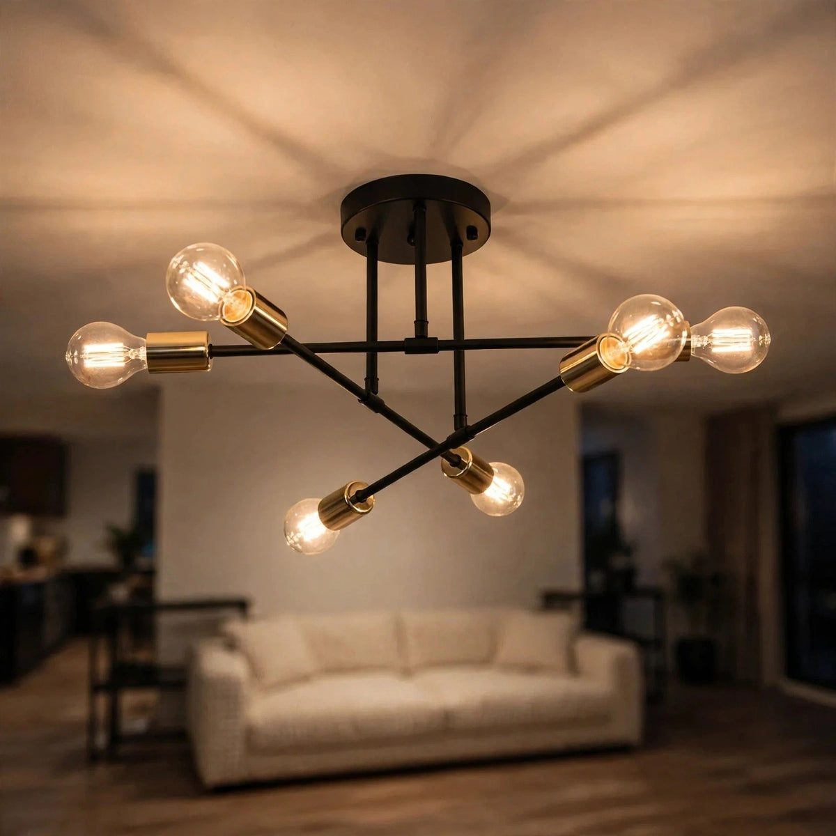 A black chandelier with gold-toned sockets and six glowing clear bulbs hangs above a cream sofa, casting ceiling shadows.