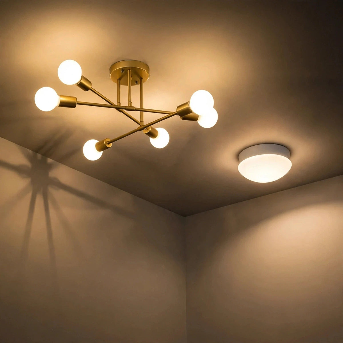 Gold-colored iron sputnik chandelier with six glowing globe bulbs mounted on a warm-toned ceiling above a room corner.