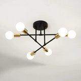 Black and gold sputnik chandelier with six glowing globe bulbs on a black iron frame against a light background.