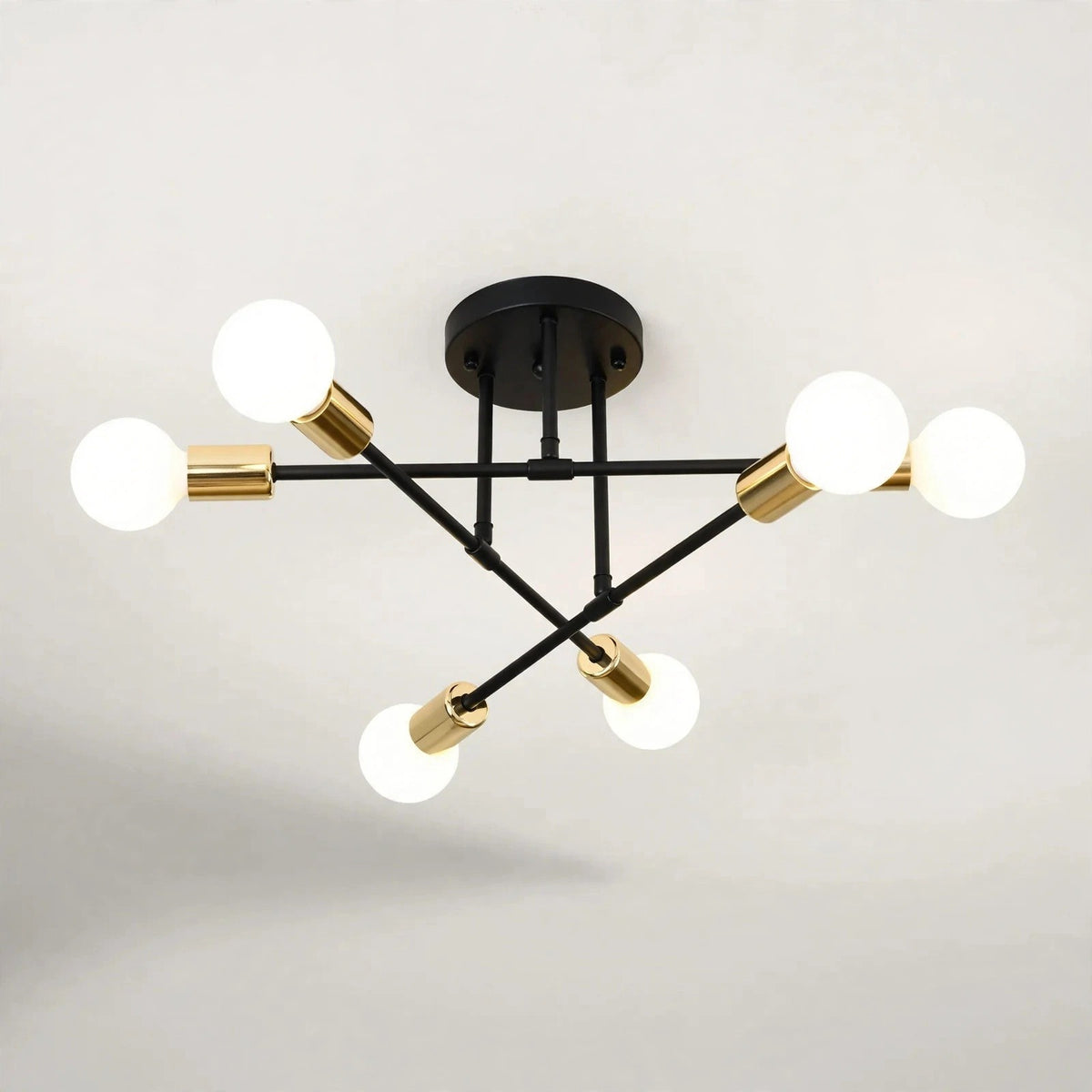 Black and gold sputnik chandelier with six glowing globe bulbs on a black iron frame against a light background.