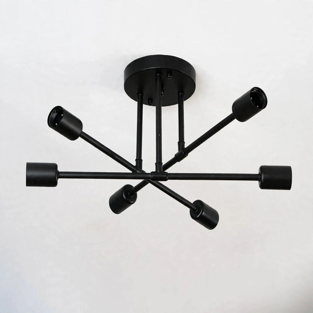 Black iron sputnik chandelier with six bare sockets on branching arms against a plain light background.