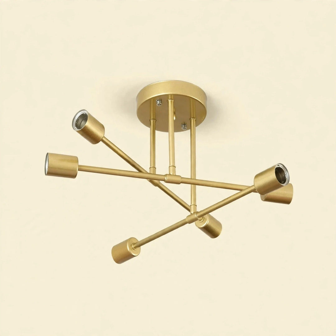 Gold-colored iron sputnik chandelier with six cylindrical sockets on crossing arms against a cream background.