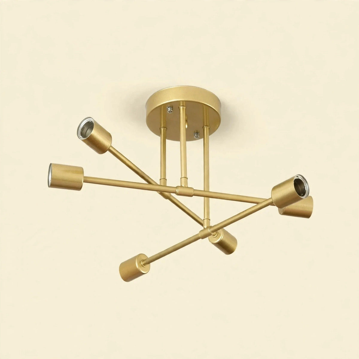 Gold-colored iron sputnik chandelier with six cylindrical sockets on crossing arms against a cream background.