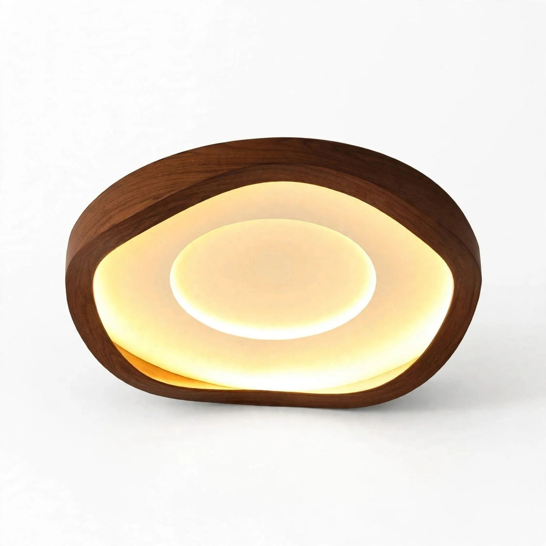 Brown wood-grain ceiling light with an irregular rounded outline and illuminated cream diffuser, displayed at an angle against a white background.