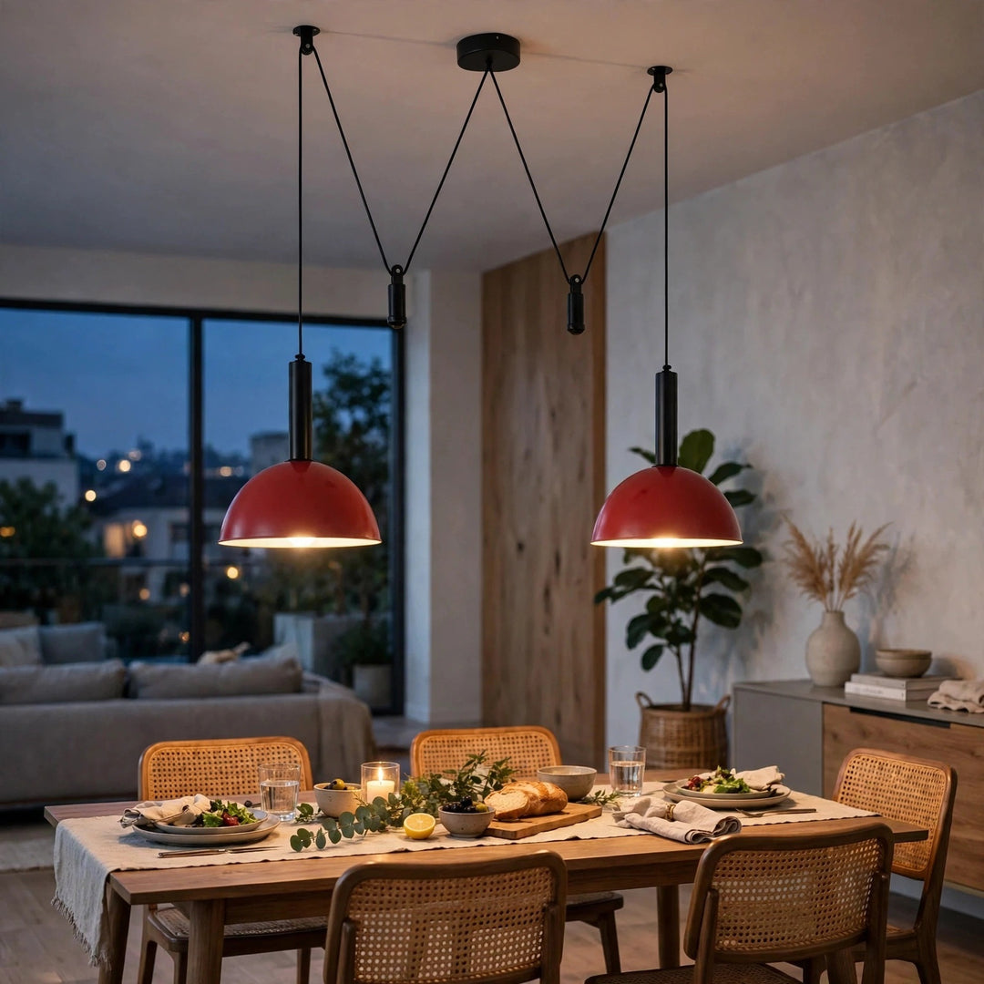 Two red dome pendant lights hanging over a wooden dining table in a modern, warmly lit dining room.