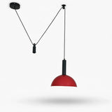 A modern adjustable pendant light with a red dome-shaped shade and black cord suspension system, shown against a plain white background with a soft shadow underneath.