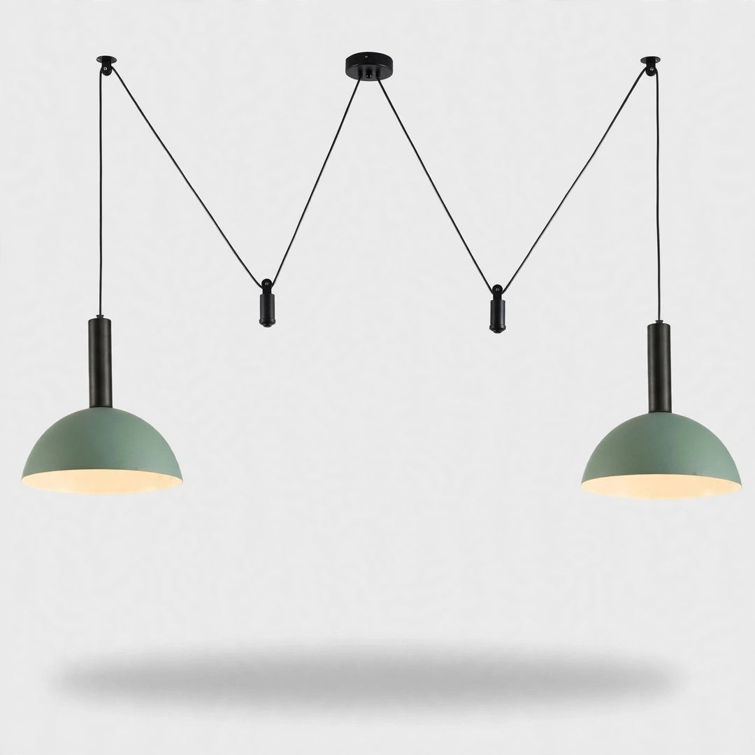 A modern two-light pendant ceiling fixture with sage green dome shades and black cords, suspended against a light gray background.
