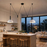 Modern kitchen island with a white marble countertop and light wood base, styled with woven bar stools. Two black pendant lights with white dome shades hang above the island.