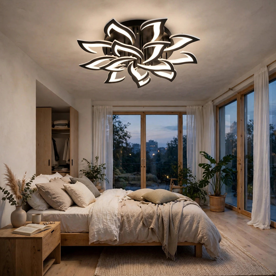 A modern flower-shaped ceiling light fixture with white petals and black accents, glowing in a beautifully styled bedroom with wooden floors, a bed, and large windows.