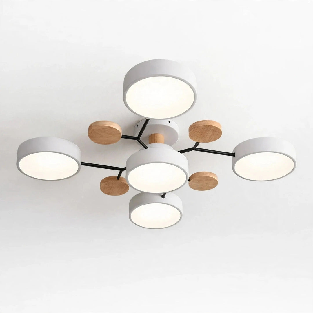 Modern ceiling light fixture with five white cylindrical shades, black branching arms, and five small natural wood round accents, shown against a plain white ceiling.