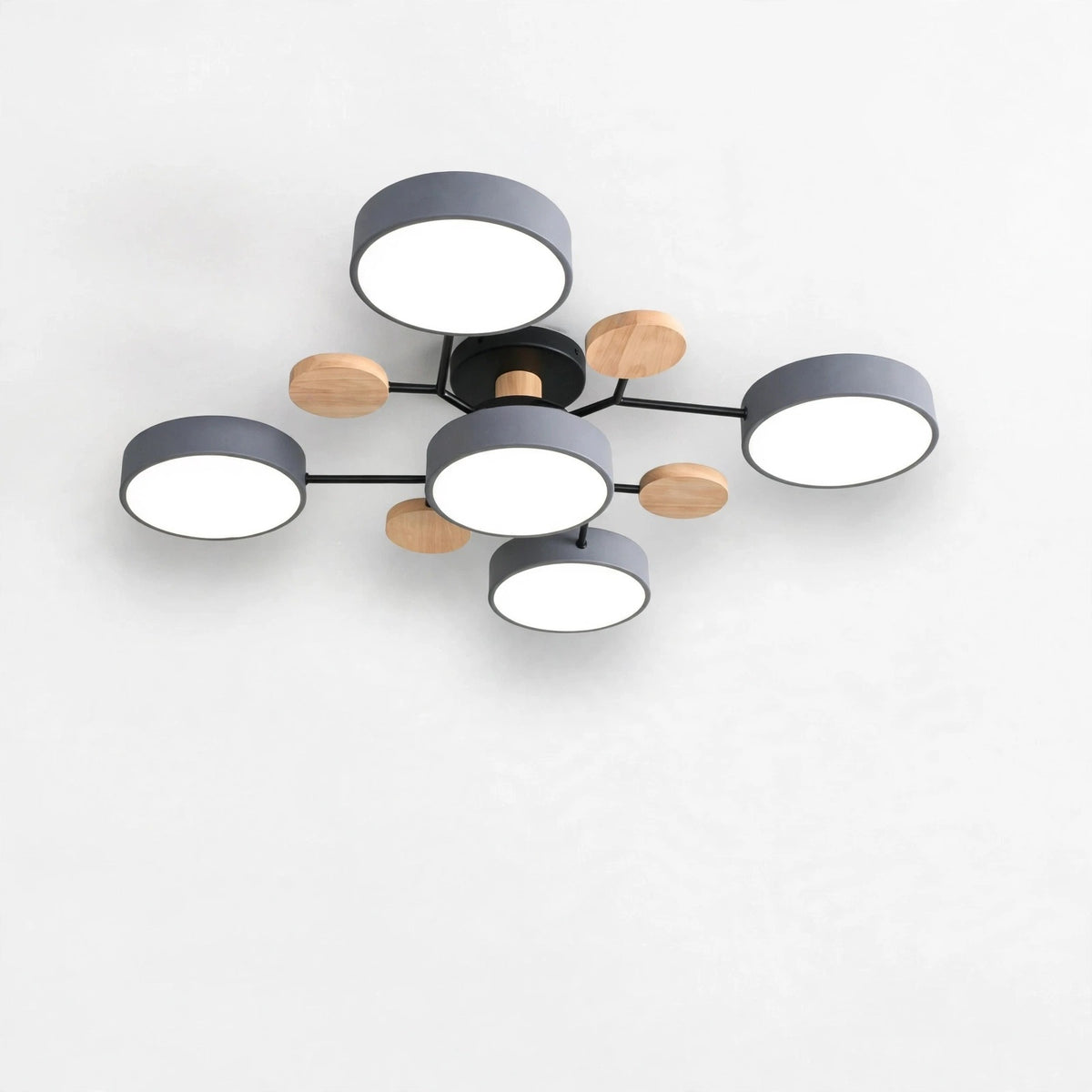 Modern multi-light ceiling fixture with six circular white shades, dark gray cylindrical rims, and natural wood accents on a black metal frame, shown against a plain white wall.