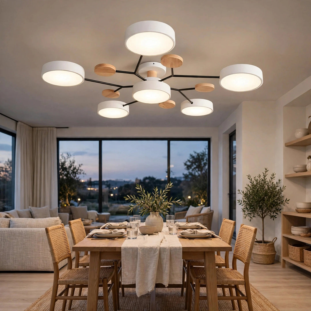 Six-light ceiling fixture with white circular shades, black branching arms, and wood-toned accents above a set wooden dining table.