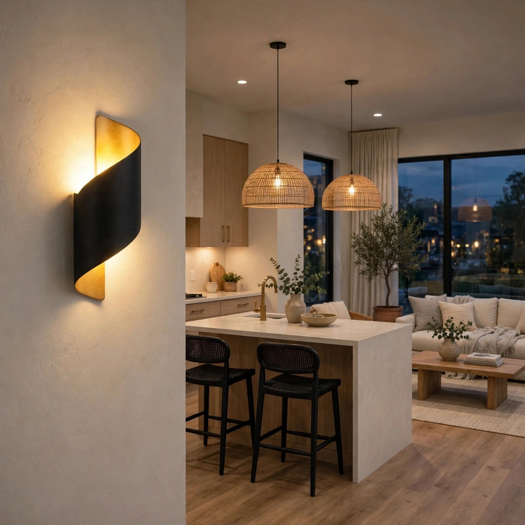 A modern wall-mounted spiral sconce with a black outer frame and warm gold inner panel, glowing in a contemporary kitchen and living room setting.
