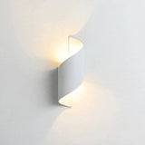A modern spiral-shaped wall sconce light fixture in a matte white finish, emitting a warm yellow glow against a clean white wall.