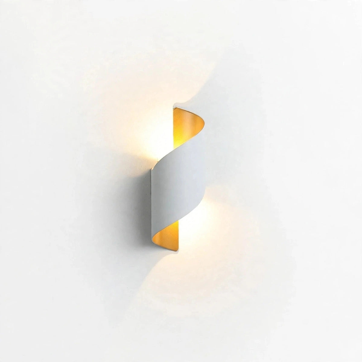 A modern spiral-shaped wall sconce with a white outer body and a warm yellow-gold inner panel, shown illuminated against a plain white wall.