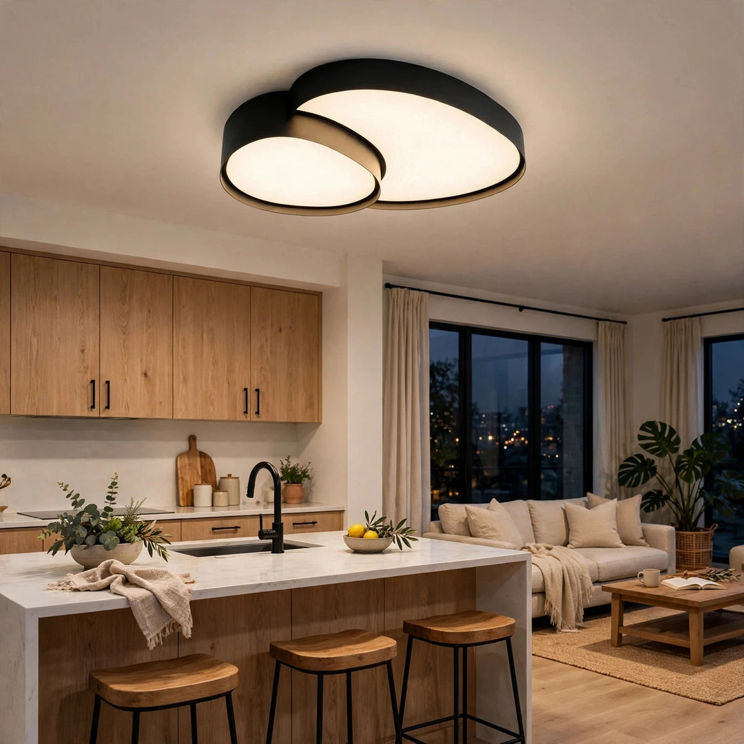Modern two-ring flush mount ceiling light with black metal frames and warm white glowing diffusers, installed in a contemporary kitchen and living room setting.