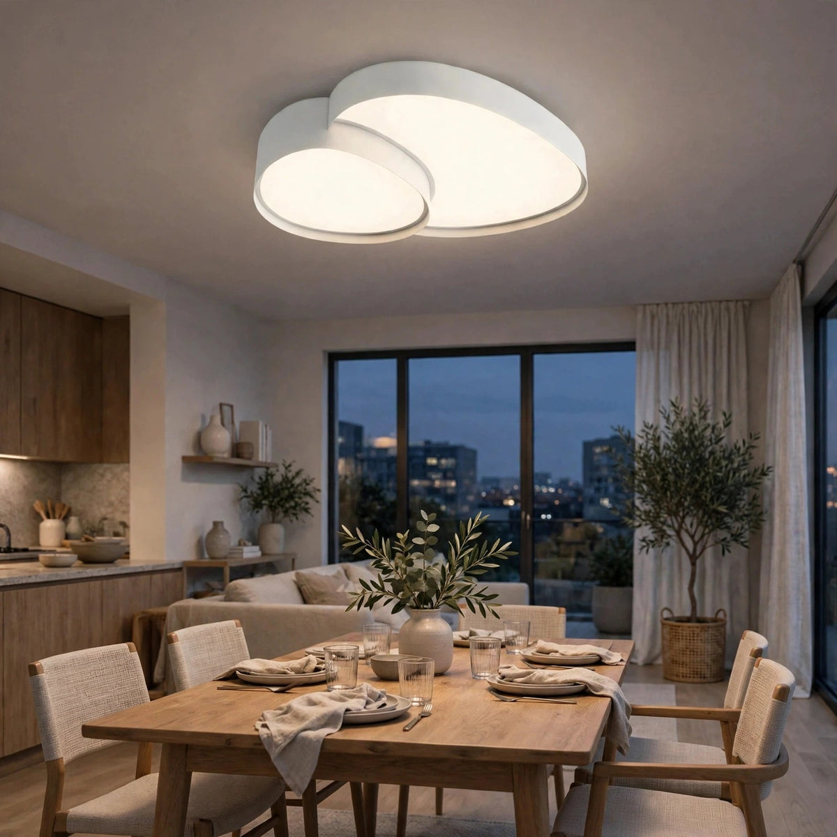 A modern double-ring LED ceiling light fixture with a white finish, glowing in a contemporary dining room setting with a wooden dining table and chairs.