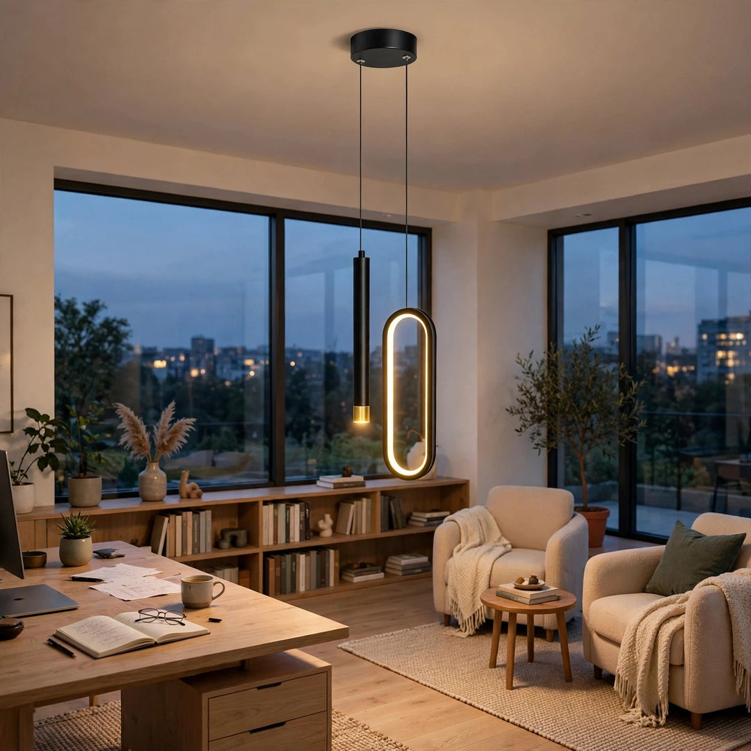 Modern living room with two pendant lights hanging over a desk and seating area. One light has a matte black cylindrical shade, and the other has an elongated oval frame with a warm glowing LED edge.