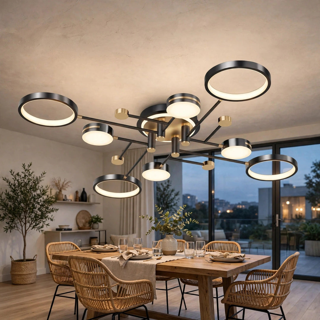 A black ceiling light with circular rings and gold accents glows above a wooden dining table surrounded by woven chairs.