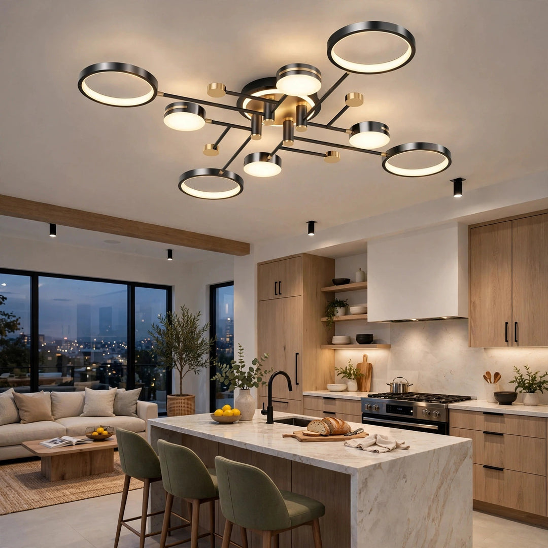 A black ceiling light with circular rings and gold accents illuminates a kitchen with wooden cabinets, a white island, and green stools.