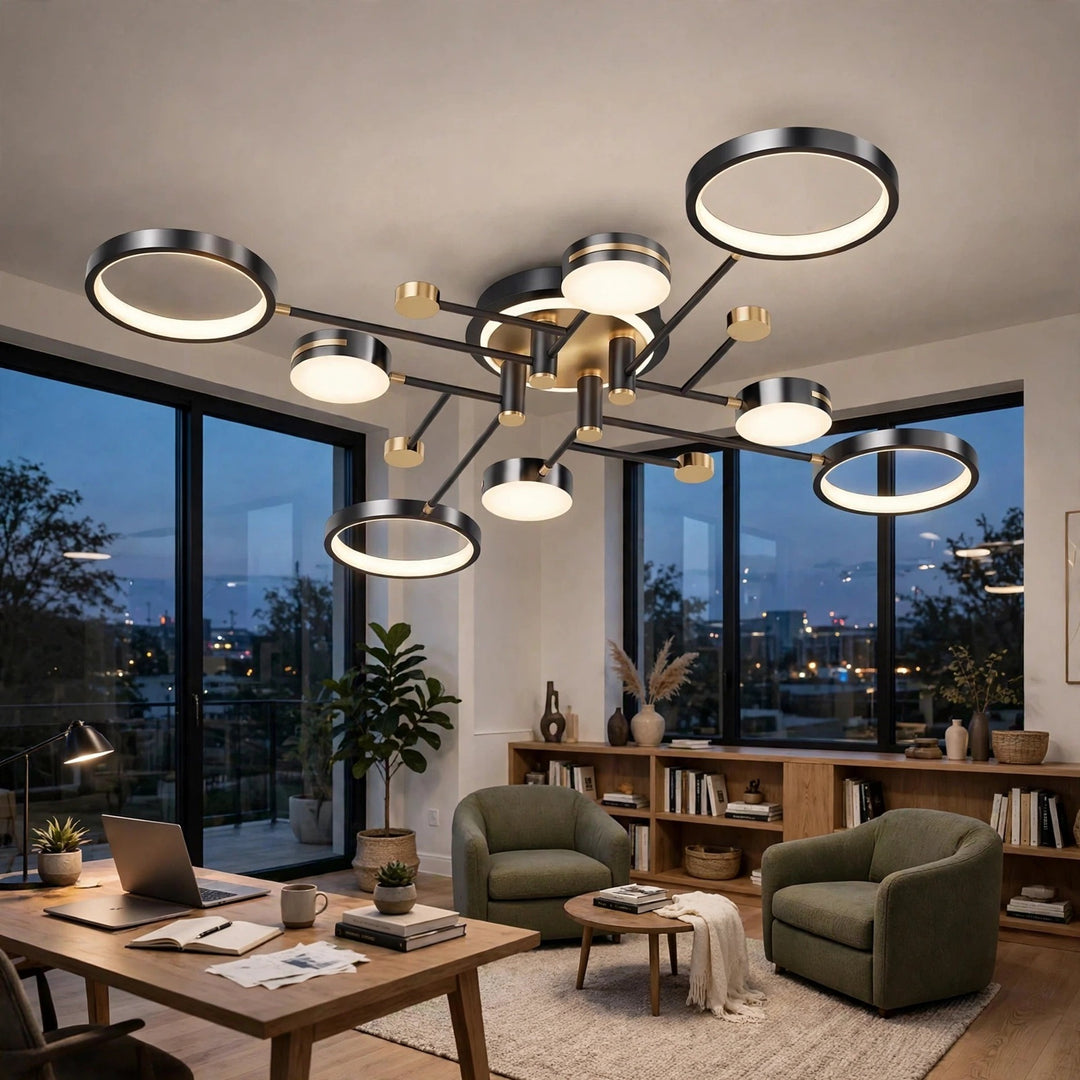 A black ceiling light with circular rings and gold accents glows above a home office with green armchairs and a wooden desk.