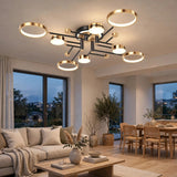 A ceiling light with gold circular rims and black arms glows above a cream sofa and wooden dining table at dusk.