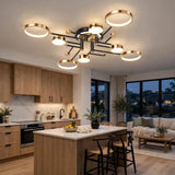 A ceiling light with gold circular rims and black arms illuminates an open kitchen with wooden cabinets and a white island.