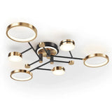 Modern ceiling light fixture with a black metal frame, gold accents, and five circular ring-shaped LED lights, shown against a plain white background.