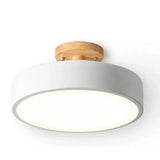 A modern semi-flush mount ceiling light with a matte white cylindrical shade, a natural light wood ceiling mount, and a glowing white frosted glass diffuser, shown against a plain white background.