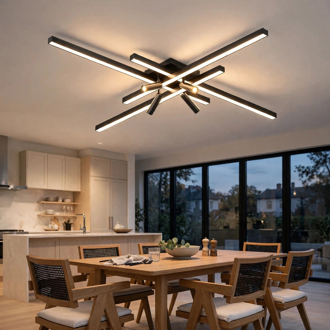 Modern ceiling light fixture with multiple intersecting linear LED bars in a black finish, installed in a contemporary dining room with wooden chairs and a table.