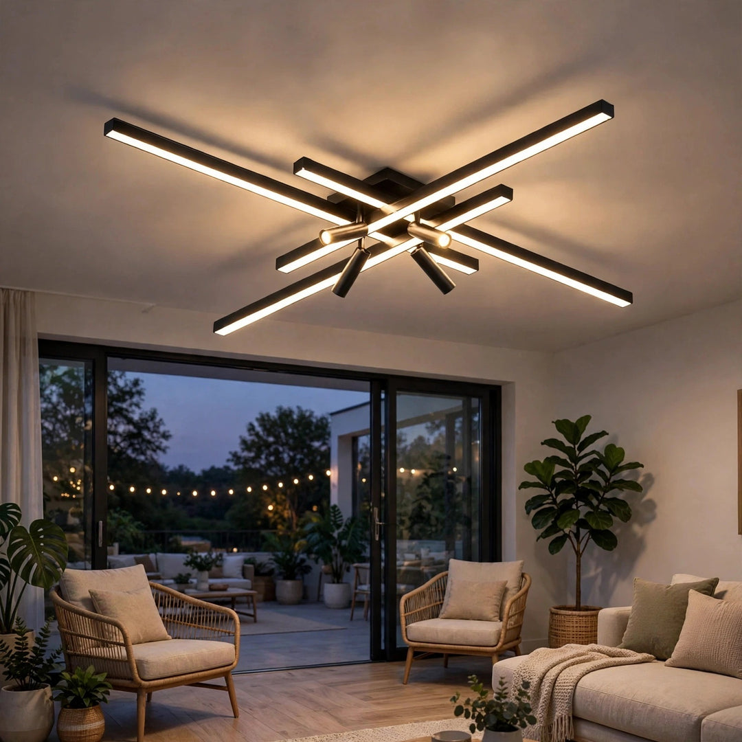 Black crossed linear-bar ceiling light glows in a living room with rattan armchairs and glass doors opening to a patio at dusk.