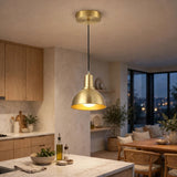 A modern brass pendant light with a conical dome shade hanging over a contemporary kitchen and dining area.