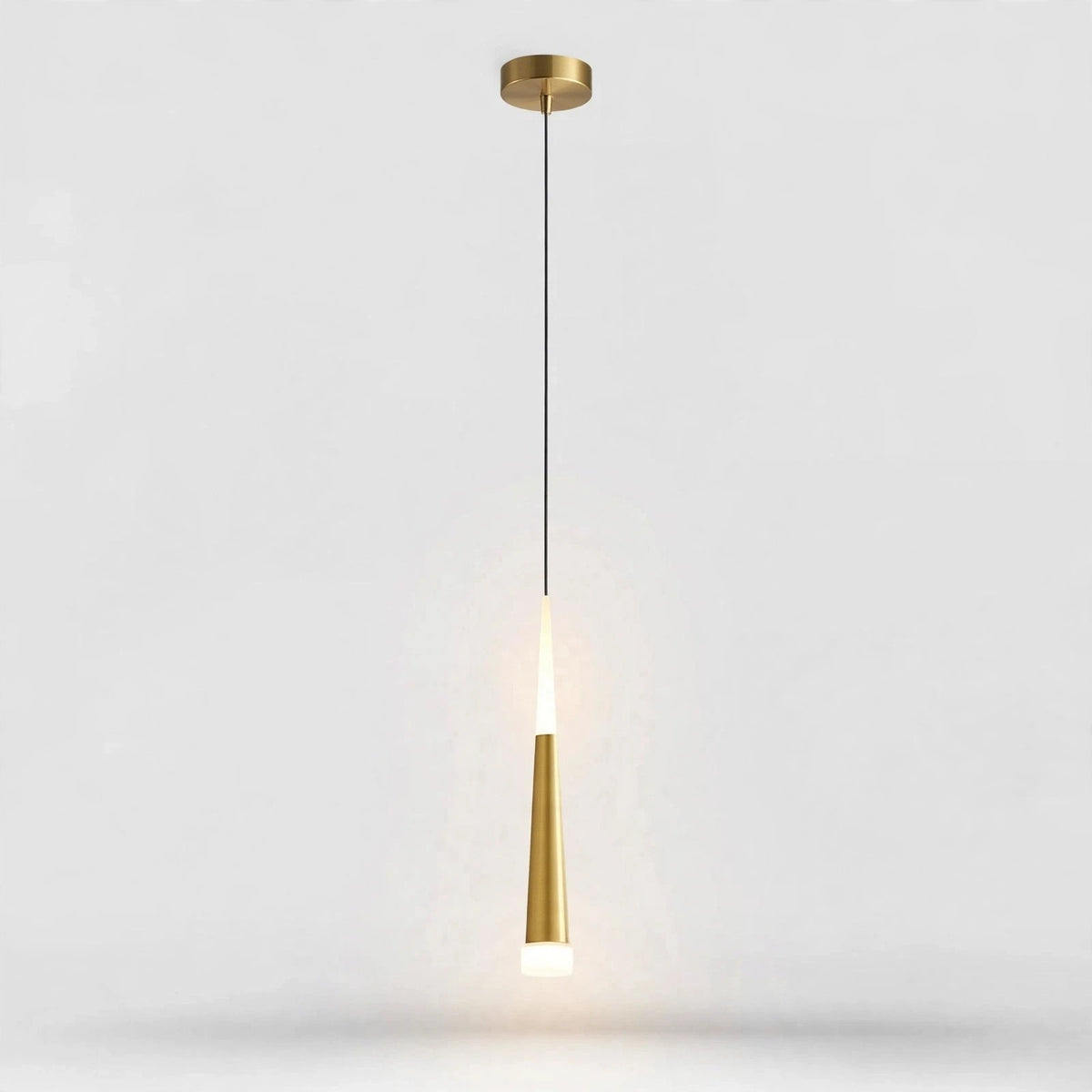 A modern pendant light fixture with a brushed gold ceiling canopy and a tapered gold shade, suspended by a thin black cord against a light gray background.