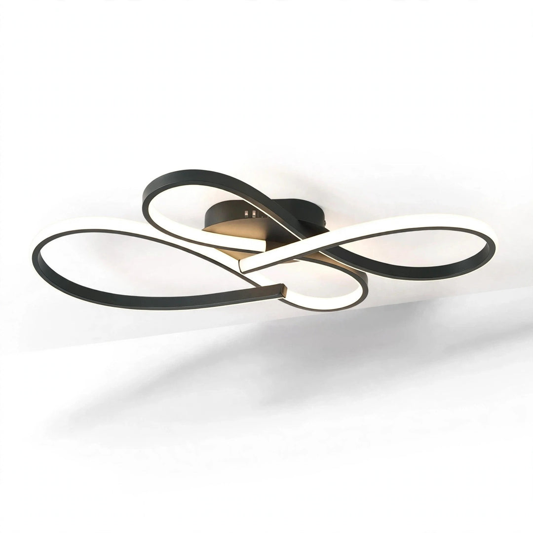 Modern ceiling light fixture with interlocking curved bands in black and white, mounted on a white ceiling with a soft shadow below.