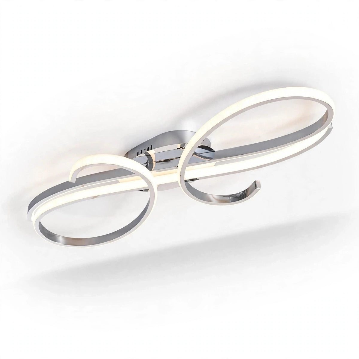 A silver ceiling light with glowing curved strips and a reflective round mounting base appears in an angled close-up against white.
