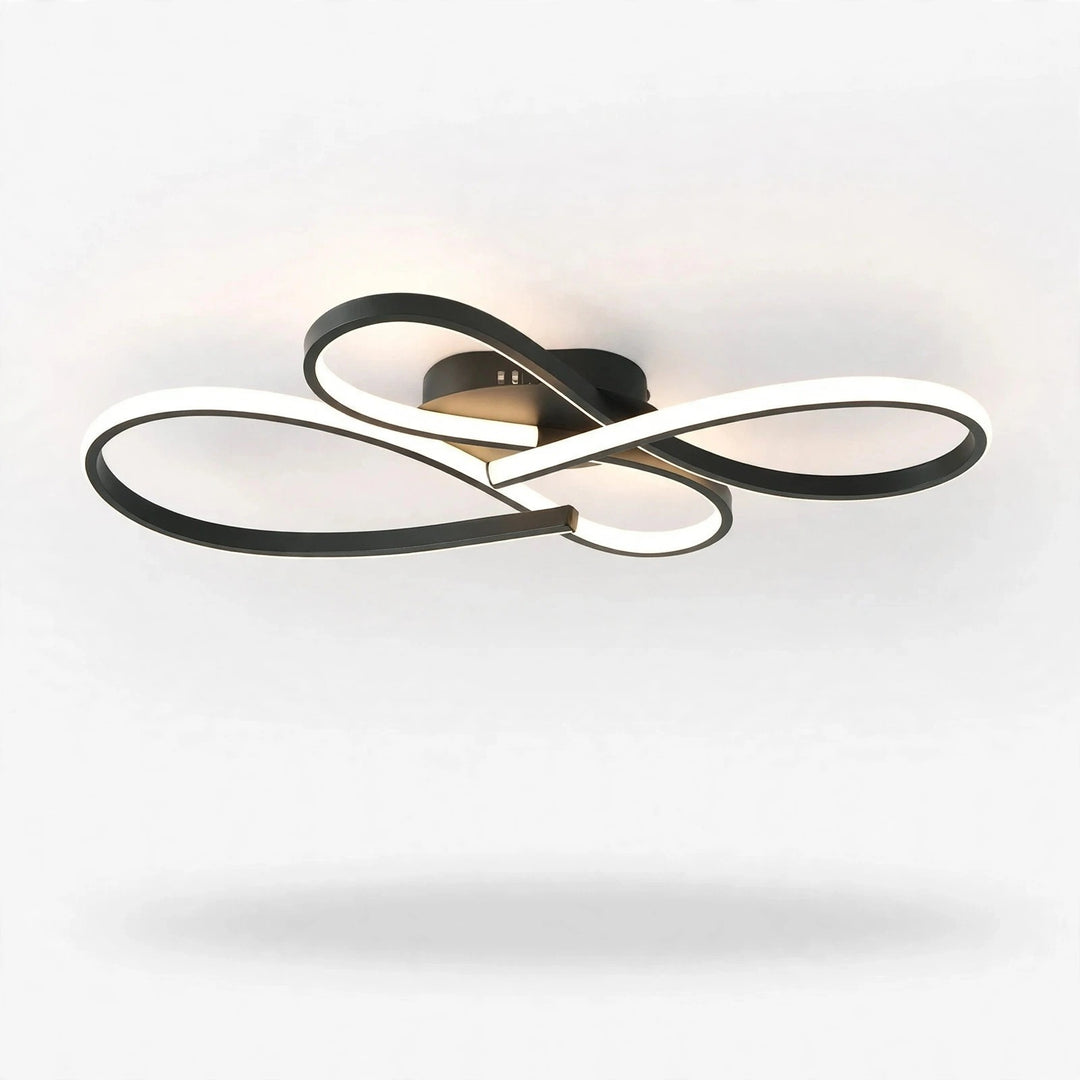 Modern ceiling light fixture with interlocking curved rings in black and white, shown illuminated against a plain white ceiling.