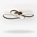 Modern ceiling light fixture with interlocking curved rings in black and white, shown illuminated against a plain white ceiling.