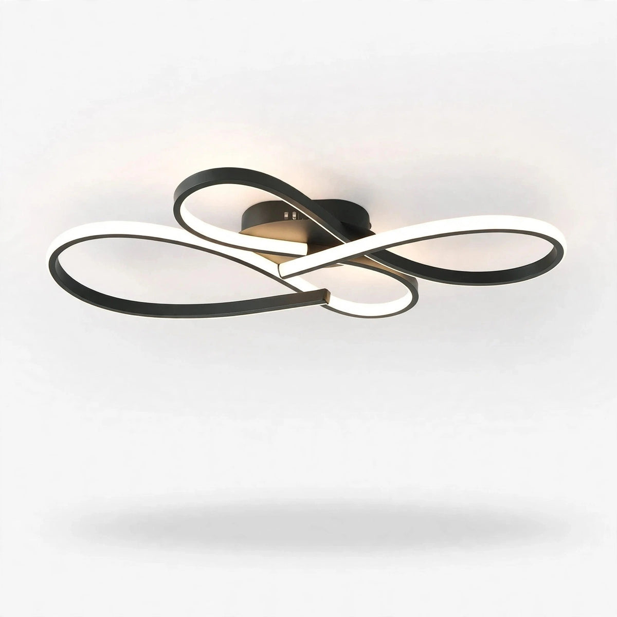 Modern ceiling light fixture with interlocking curved rings in black and white, shown illuminated against a plain white ceiling.