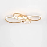 Modern ceiling light fixture with interlocking gold and white LED loops, shown mounted against a plain white wall.
