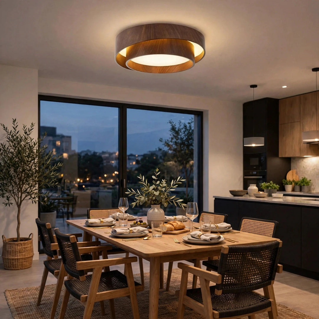 A modern semi-flush mount ceiling light with a dark wood outer ring and a glowing warm white inner ring, installed in a contemporary dining room above a wooden table and chairs.
